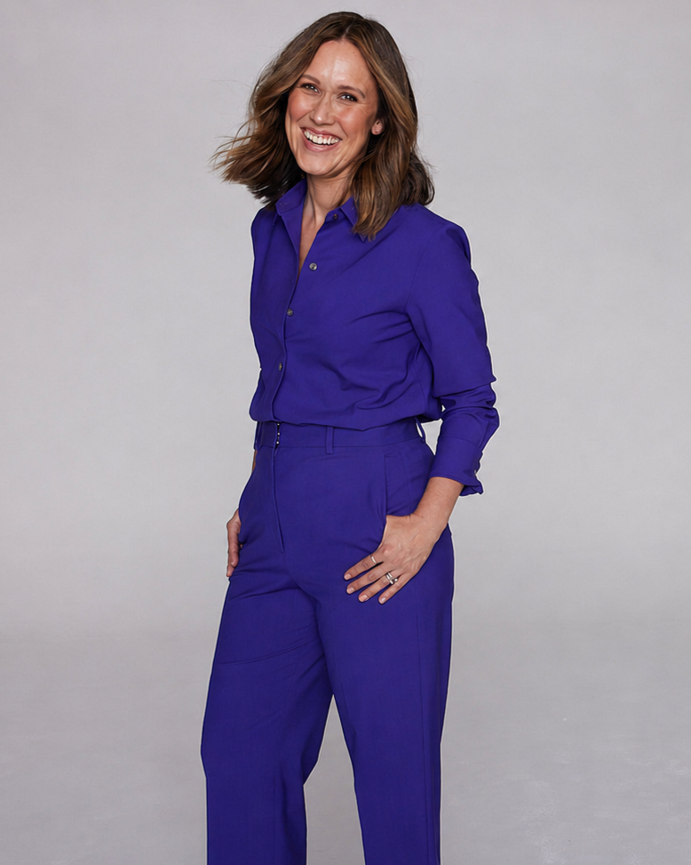 Smiling woman in a royal blue pantsuit posing against a gray studio backdrop.