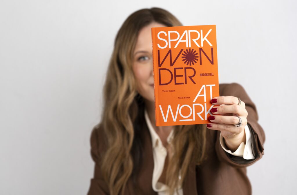 Brooke Hill holding her book, Spark Wonder at Work.